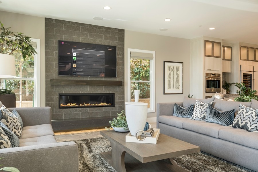 wall-mounted TV above a fireplace in a living room that has a Control4 music interface showing