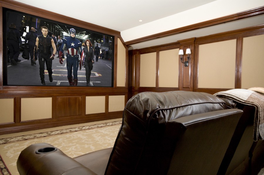 A casual home theater with brown seating and a screen depicting The Avengers. 