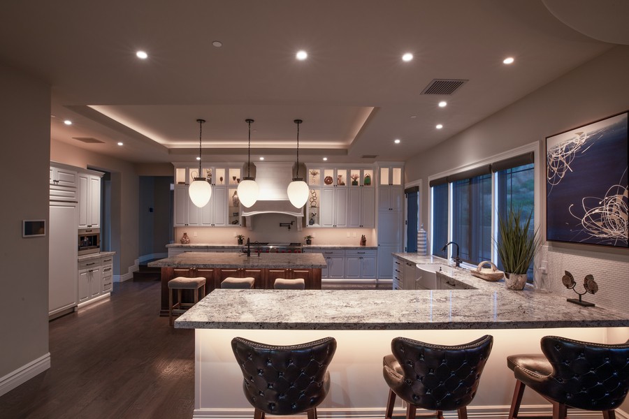 large kitchen island and seating area with automated smart lighting and pendant fixtures.