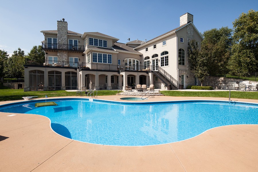 outdoor pool area with three-story home in the background.