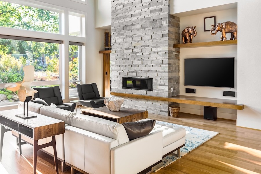 high-end media room space with couches and a wall-mounted TV with speakers beneath it.