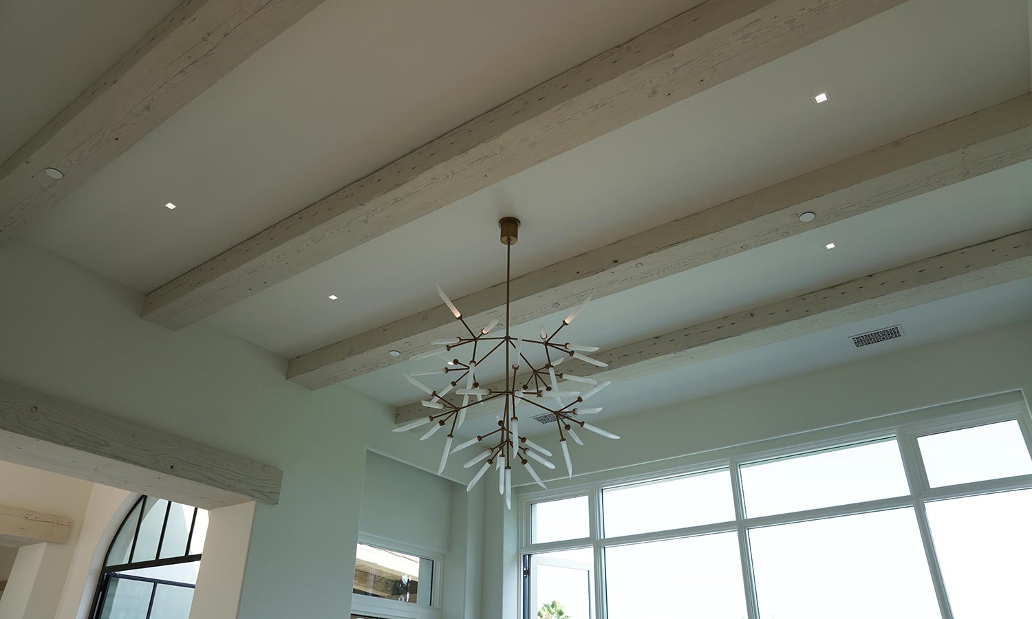 Ceiling view of modern chandelier with exposed beams