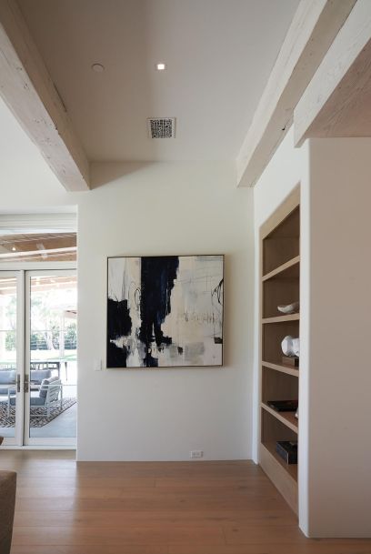 Minimalist hallway featuring abstract wall art, light wood floors, and built-in shelving