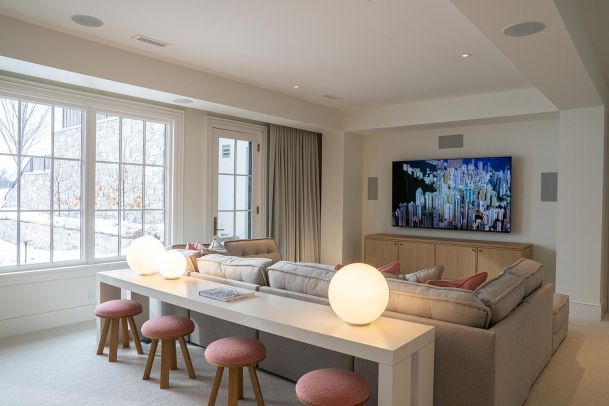 Bright living room with a large sectional, white long table, and three glowing globe lamps
