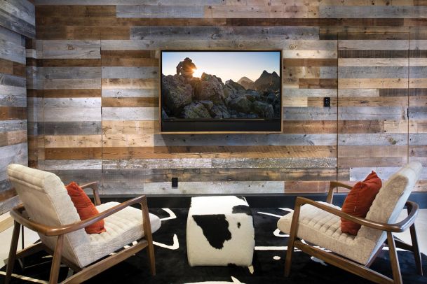 Modern lounge with reclaimed wood walls, two mid-century chairs, and a cowhide ottoman