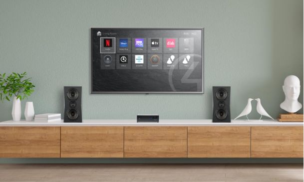 Wall-mounted television above a wood media console with two black bookshelf speakers