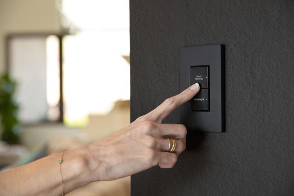 Person pressing a modern black smart wall switch