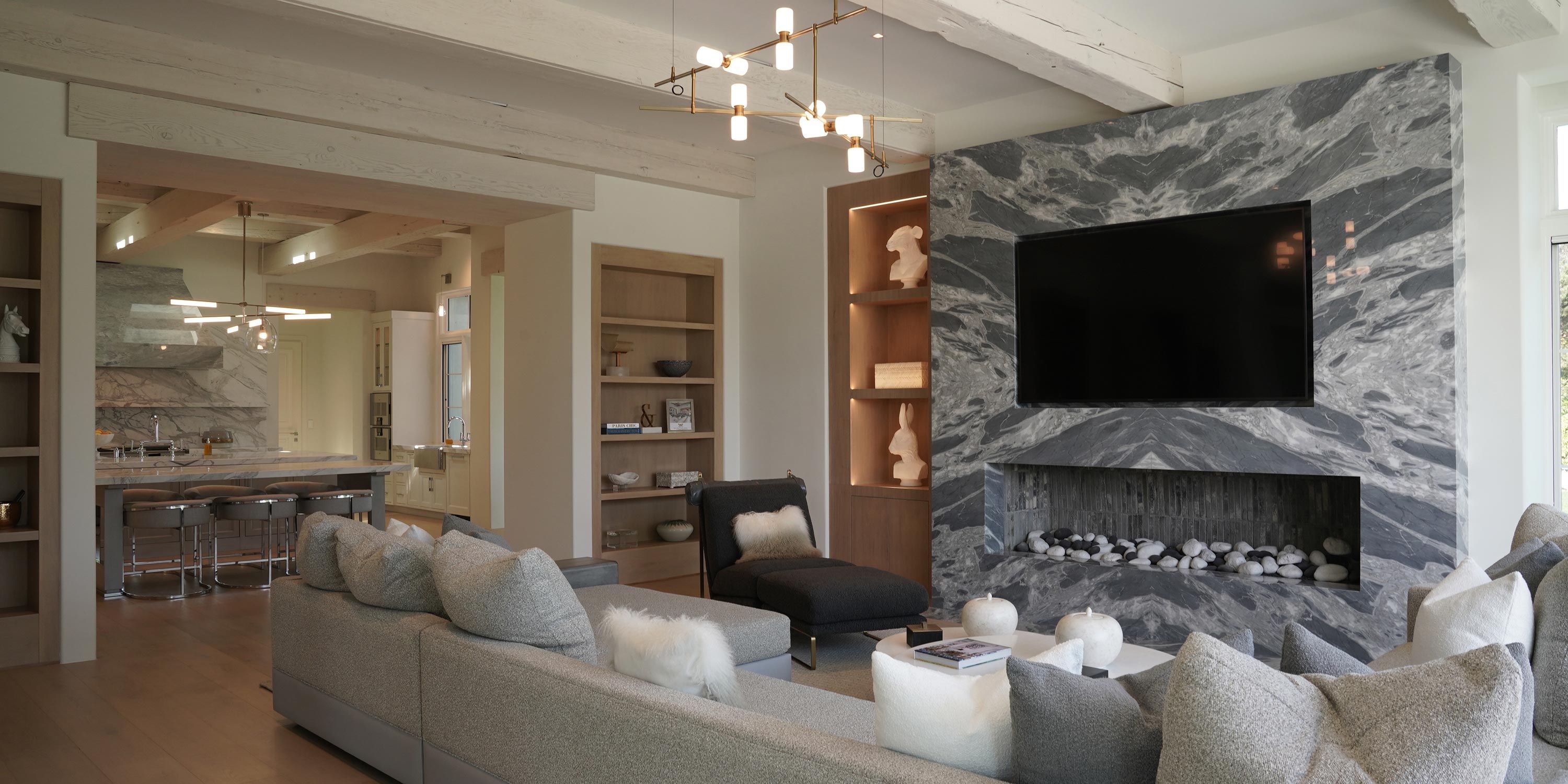 A luxurious living room featuring a marble fireplace with a mounted television, surrounded by contemporary decor.