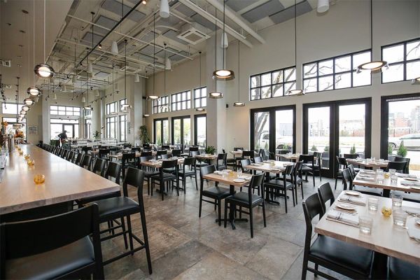 A bright and spacious restaurant interior with neatly arranged tables and chairs, showcasing modern design.