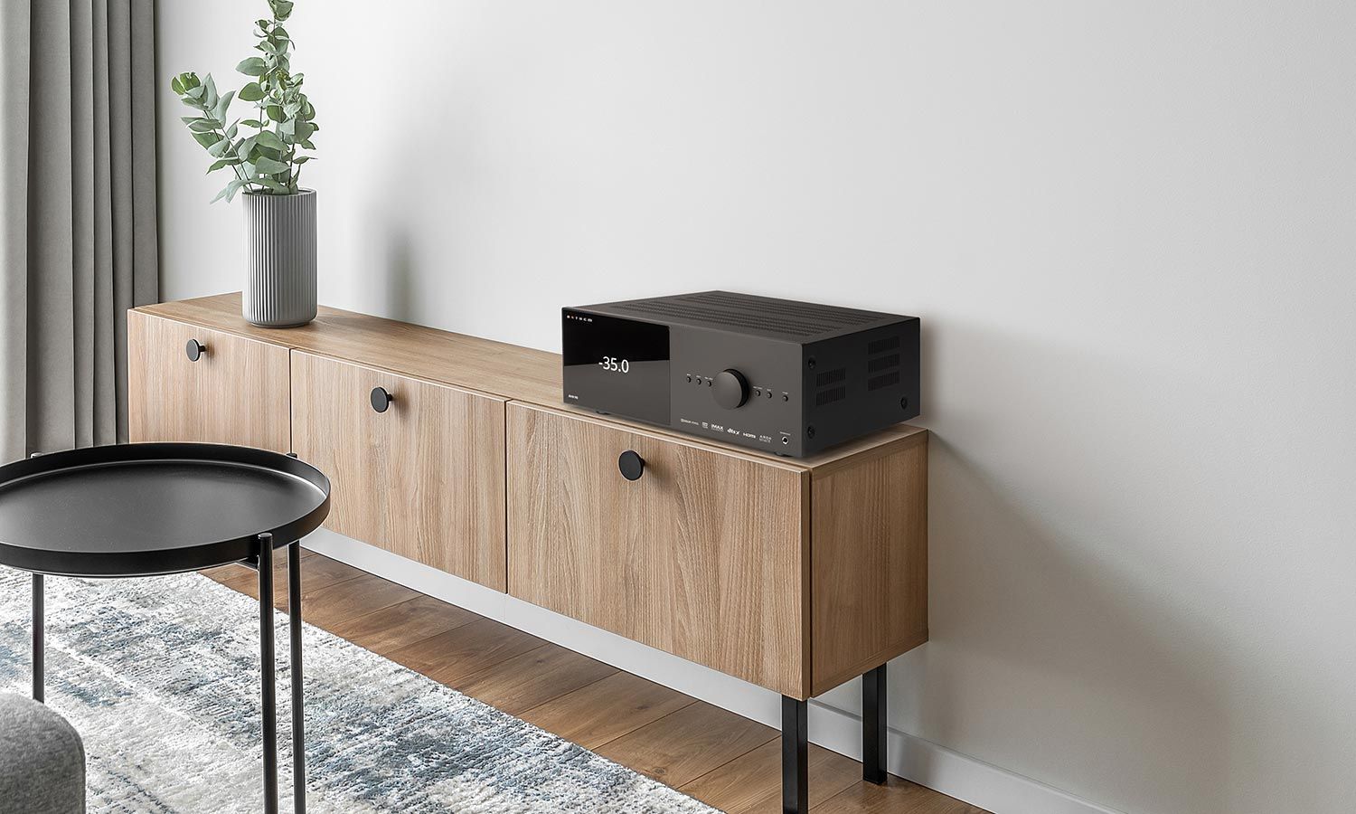 Sleek audio receiver on a wooden console in a minimalist space